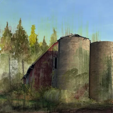 A weathered red barn and silo beside tall trees